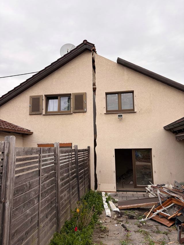 Doppelhaus mit geöffneter Trennfuge zwischen den beiden Haushälften, davor Abbruchmaterial