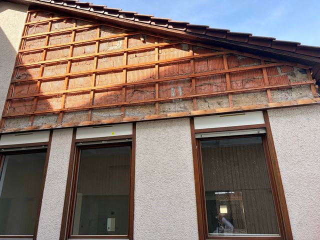 Giebelwand, deren asbesthaltige Faserzementplatten abgenommen sind, nur die Holzlattung ist noch zu sehen